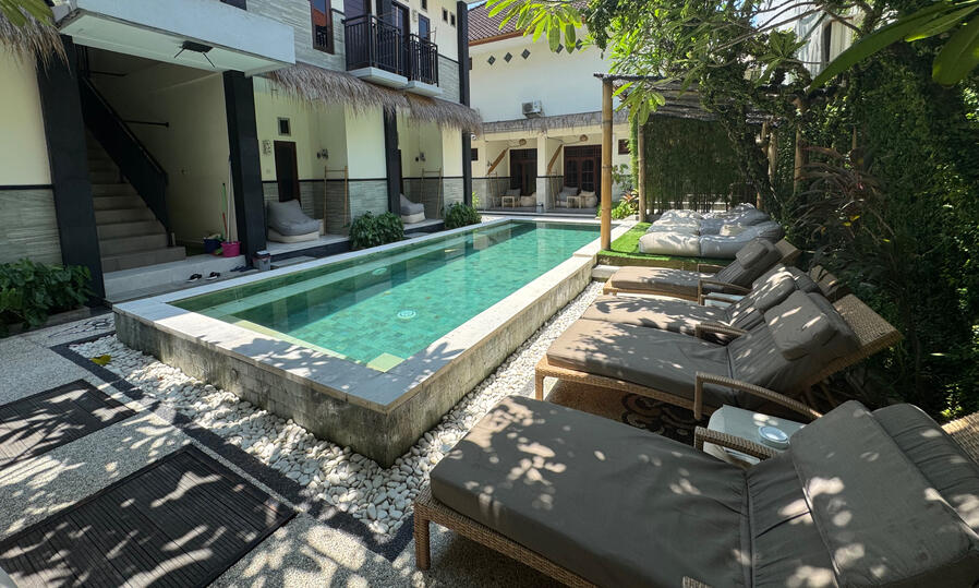 Swimming pool at Nomads Home Bali with lounge area and garden